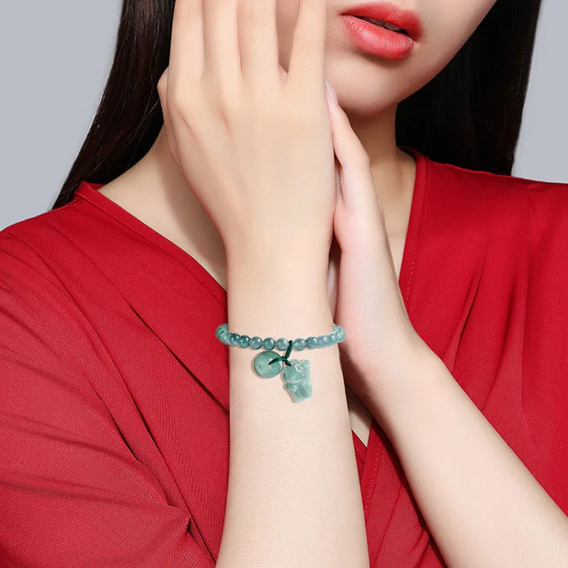 Hand woven bracelet with natural emerald beads and blue water lucky cat charm on a white background