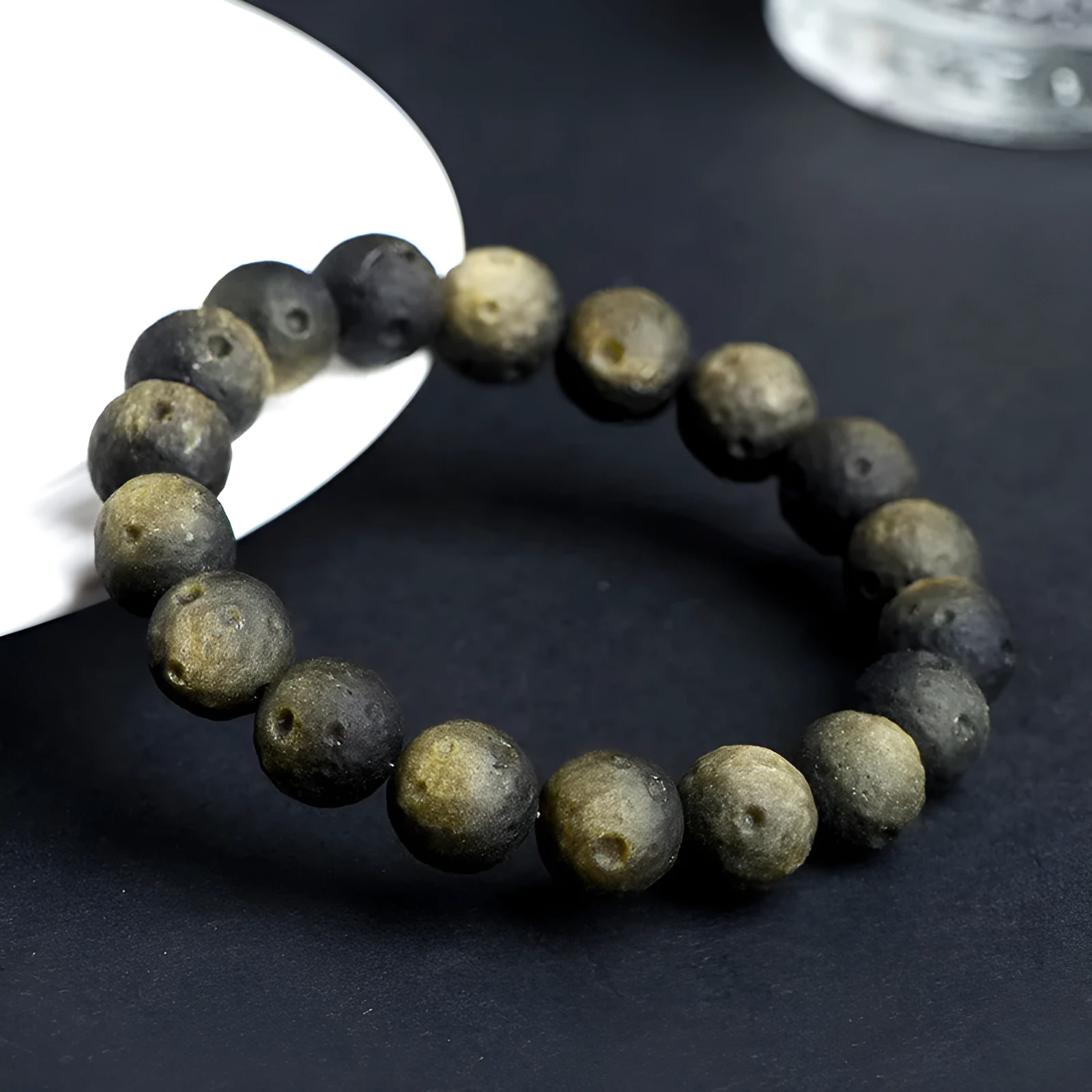 Natural obsidian crater ball bracelet with textured beads in gold or silver stone finish on a wrist.