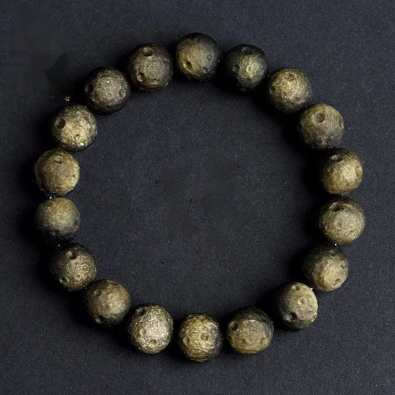 Natural obsidian crater ball bracelet with textured beads in gold or silver stone finish on a wrist.