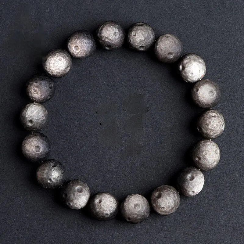Natural obsidian crater ball bracelet with textured beads in gold or silver stone finish on a wrist.