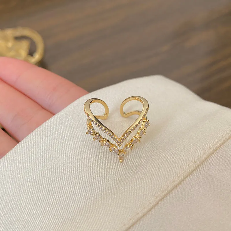 Gold plated copper heart shaped ring with full diamond detailing on white background