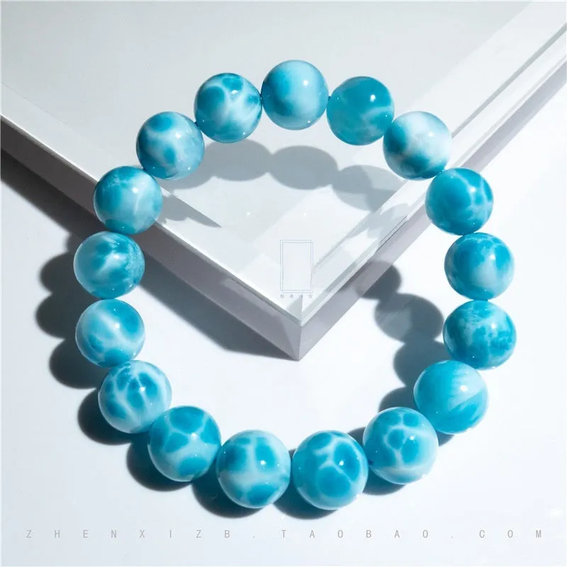Blue handmade Bodhi bead bracelet with natural crystal and sea-pattern stone on a wrist.