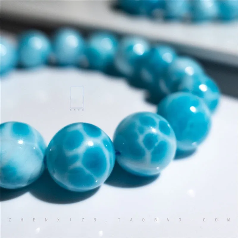 Blue handmade Bodhi bead bracelet with natural crystal and sea-pattern stone on a wrist.