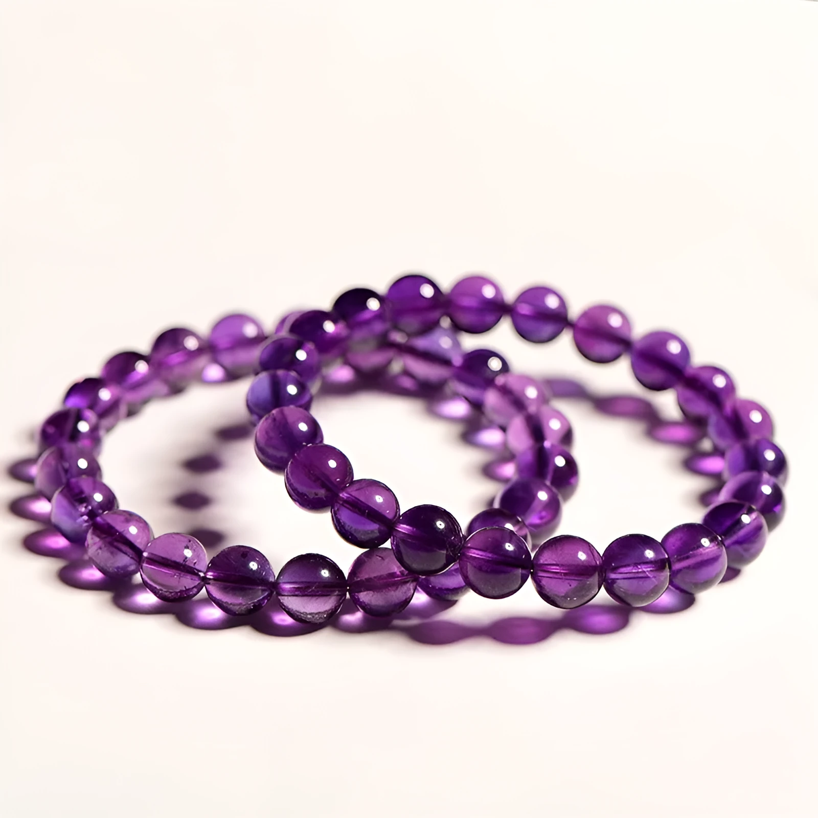 Natural amethyst Uruguay bracelet with polished purple beads, shown in single circle and triple ring designs.