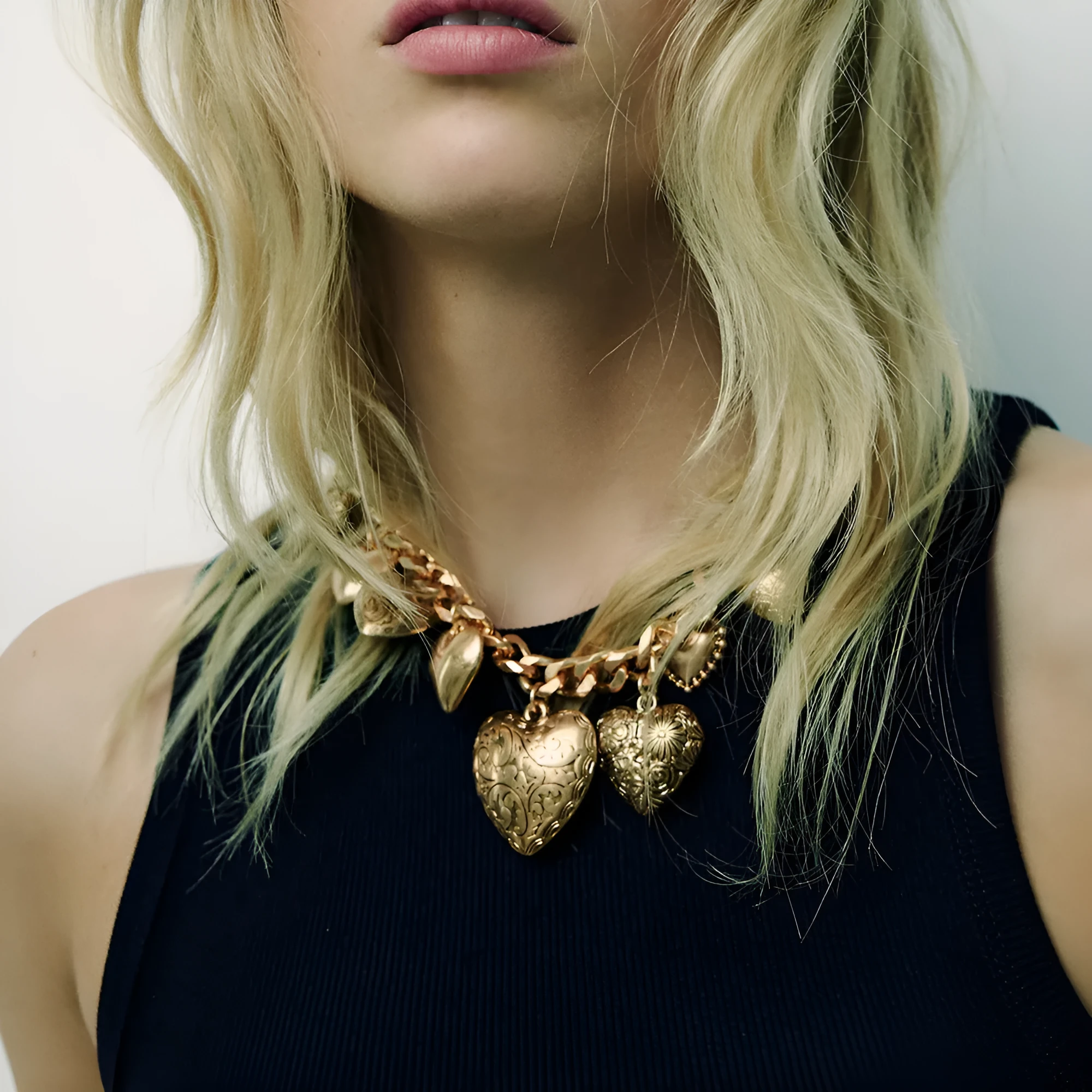 Exaggerated gold heart pendant necklace on a model, showing adjustable chain length.