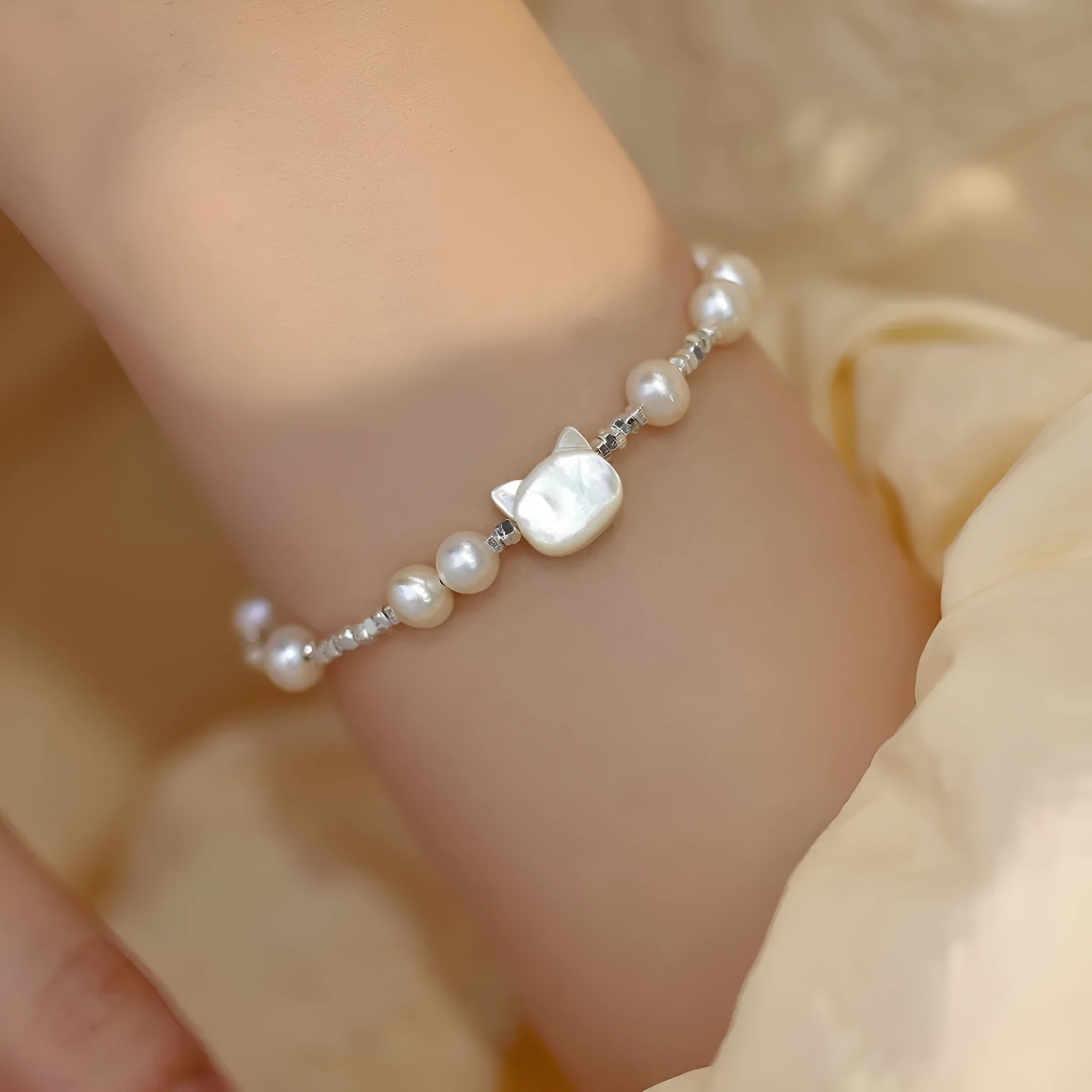 Natural freshwater pearl bracelet with Fu character charm on white background, silver chain, women's accessory