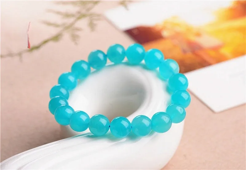 Selection of natural green Amazonite scattered beads in different sizes on a white background.