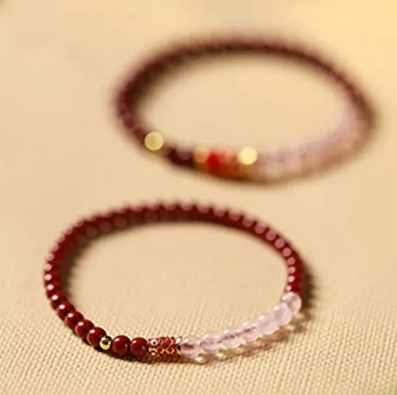 Hand-woven purple gold sand and strawberry quartz koi bracelet with crystal and pearl beads on a light background.