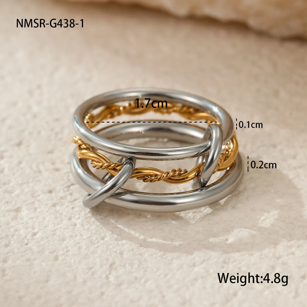 Stacked colour matching stainless steel ring with gold plating and exaggerated design on a woman's hand.
