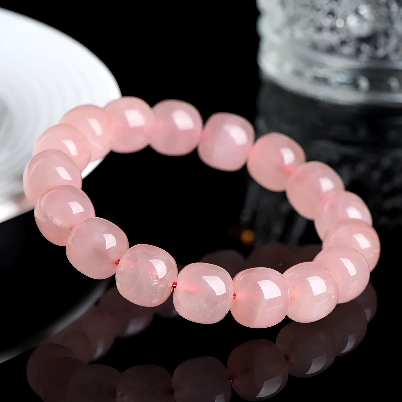 Close-up of a pink natural crystal barrel bead bracelet with geometric beads on a wrist.