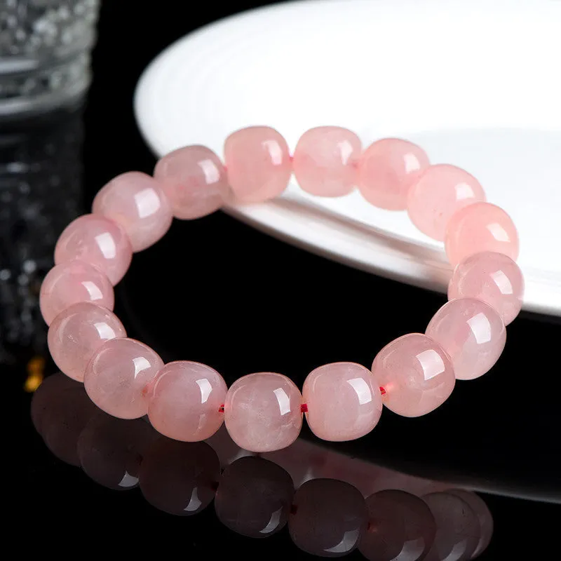 Close-up of a pink natural crystal barrel bead bracelet with geometric beads on a wrist.