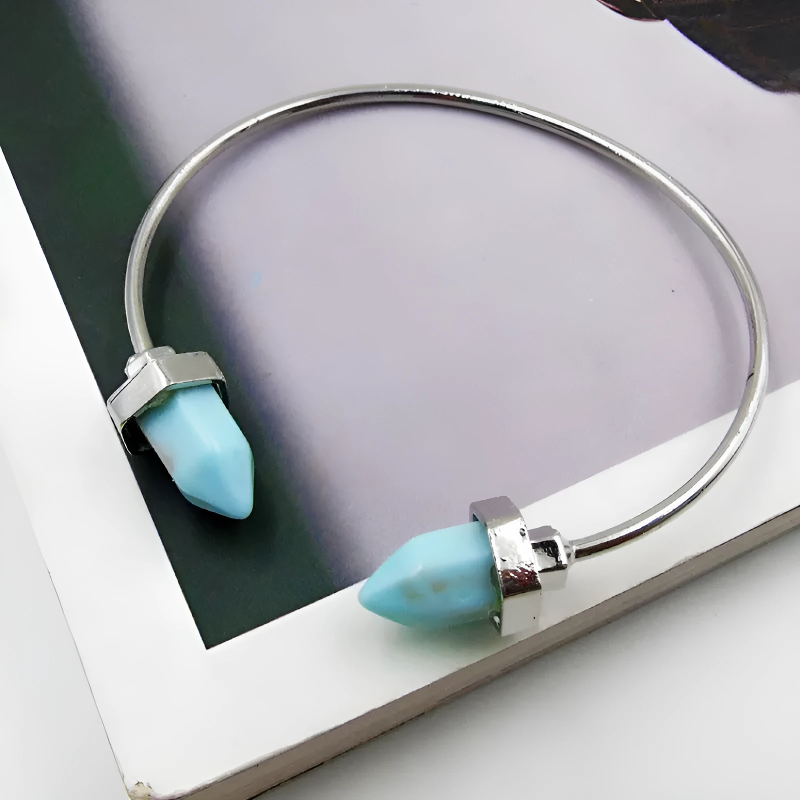 Natural alloy open-ended bracelet with inlaid gem turquoise style in silver blue finish on a neutral background