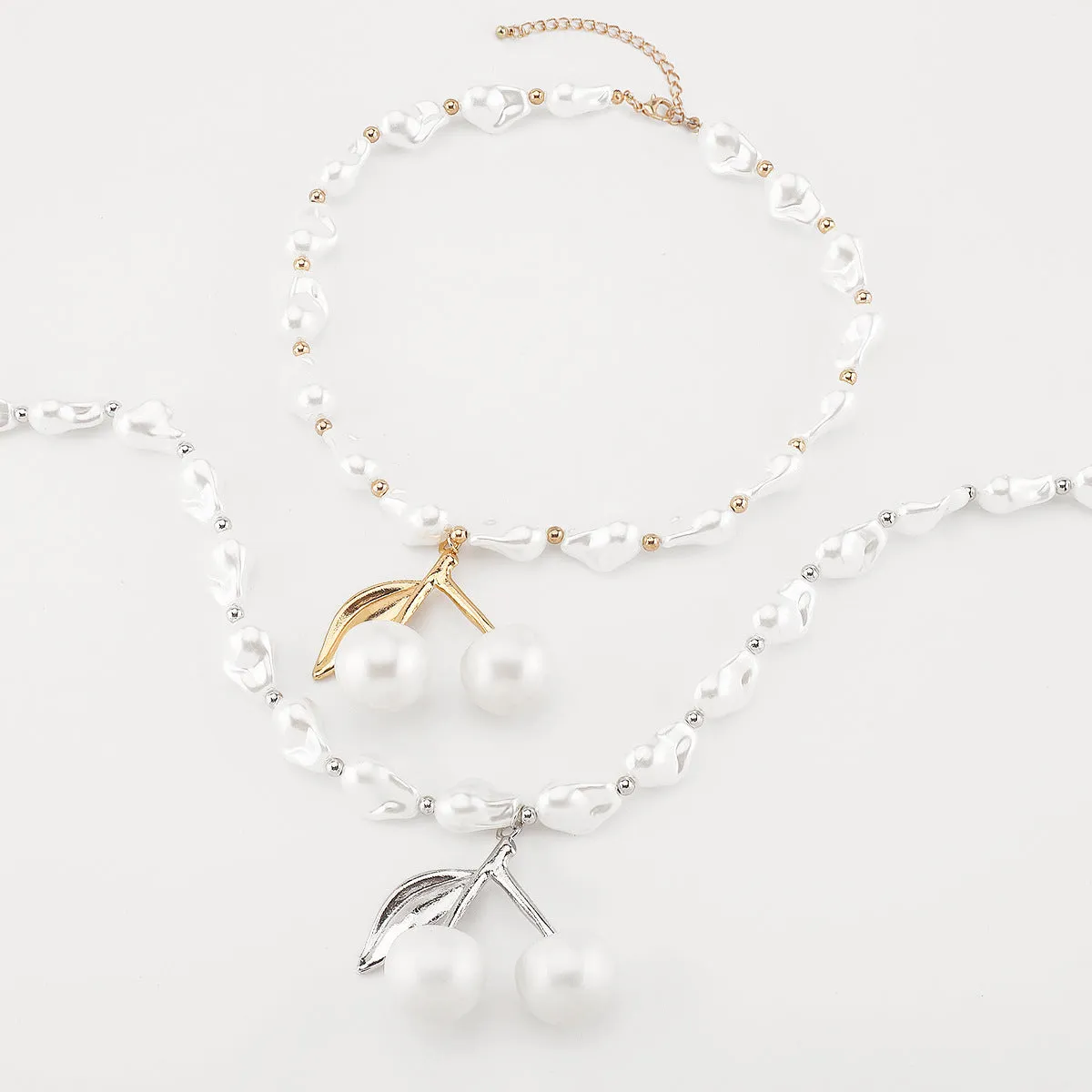 Gold-tone irregular cherry fruit pendant on an adjustable string of white imitation pearls necklace.