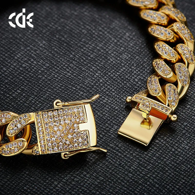 Men's Cuban chain bracelet with gold finish and geometric zircon pendant on a flat surface