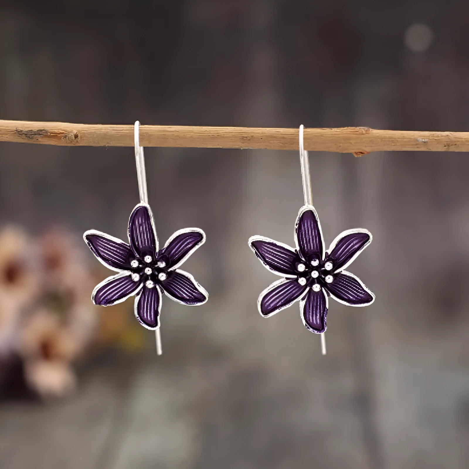 A pair of purple flower-shaped alloy stud earrings with a simple post back, shown against a plain background.