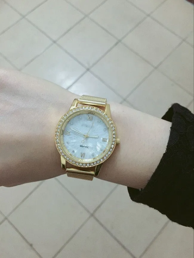 Golden mesh strap alloy electronic watch with round dial and world time GMT functions on a plain background