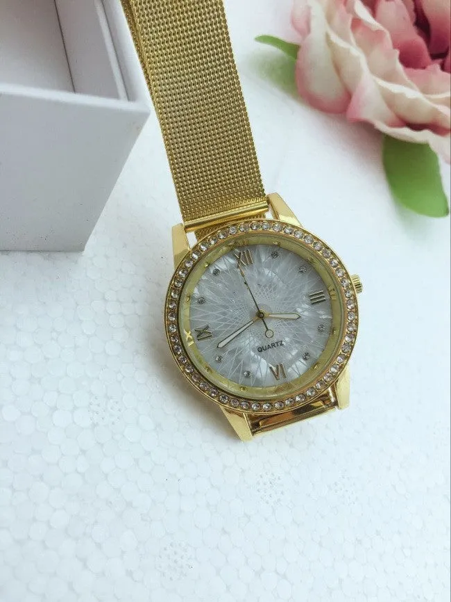 Golden mesh strap alloy electronic watch with round dial and world time GMT functions on a plain background