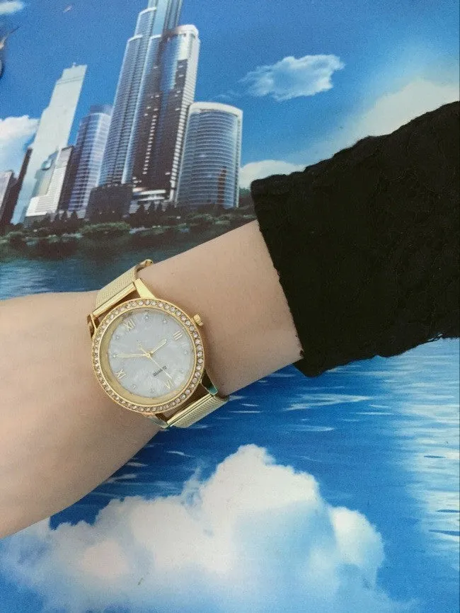 Golden mesh strap alloy electronic watch with round dial and world time GMT functions on a plain background