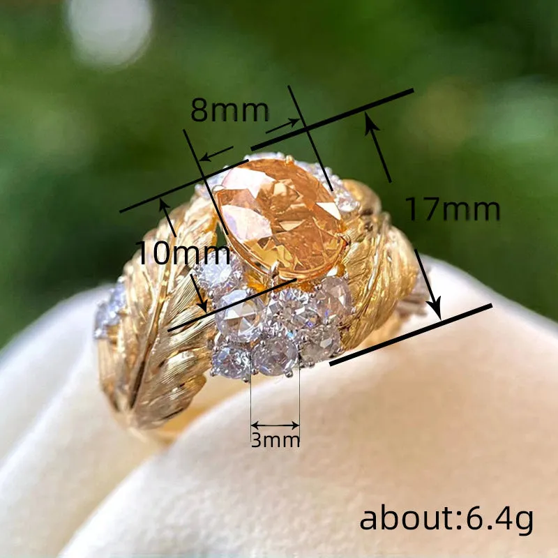 Gold-colour women's ring with an embossed feather design and a central yellow zircon stone on a finger.