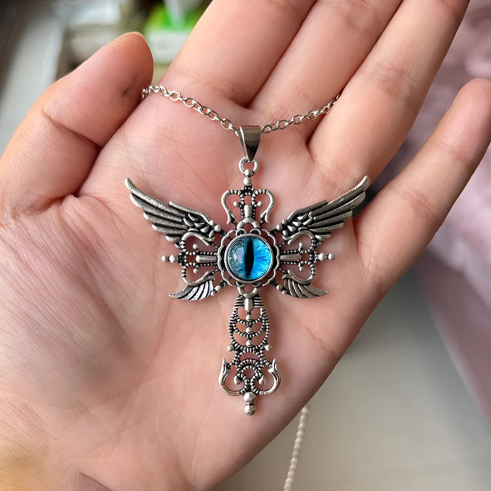 Geometric devil wings and cross alloy pendant necklace in blue on a silver chain.