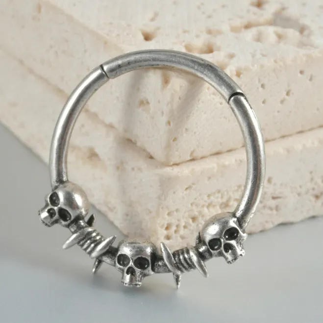 A pair of antique silver copper punk earrings featuring three small detailed ghost heads on a horizontal bar.
