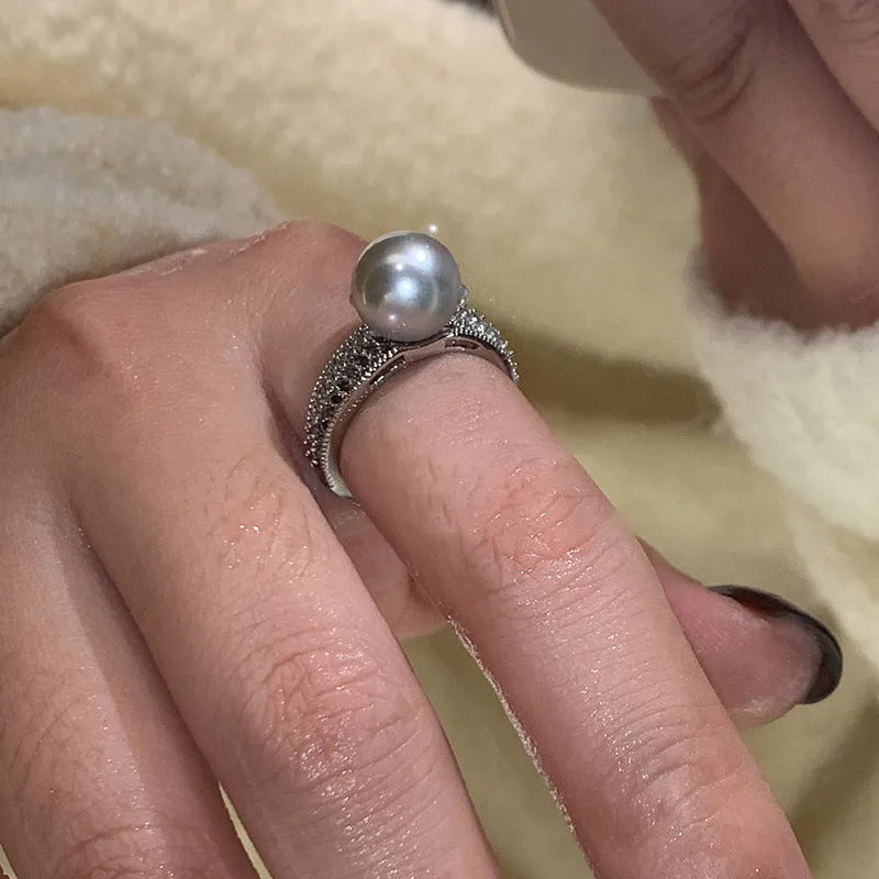 Women's adjustable copper ring with black pearl and geometric open design on an index finger.
