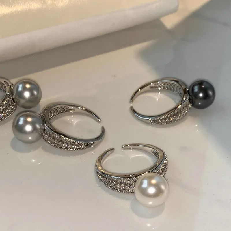 Women's adjustable copper ring with black pearl and geometric open design on an index finger.