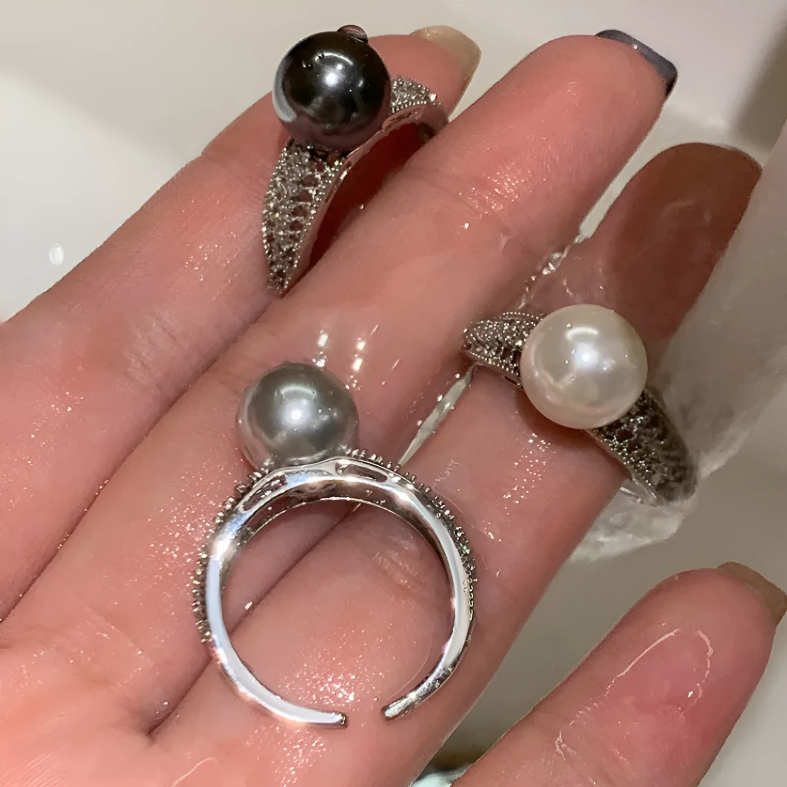 Women's adjustable copper ring with black pearl and geometric open design on an index finger.