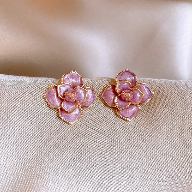 A pair of gold-plated purple oil-spot glaze flower stud earrings made from copper, showing detailed floral texture.