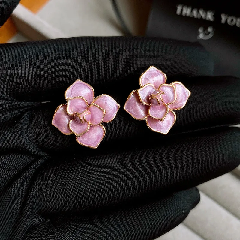 A pair of gold-plated purple oil-spot glaze flower stud earrings made from copper, showing detailed floral texture.