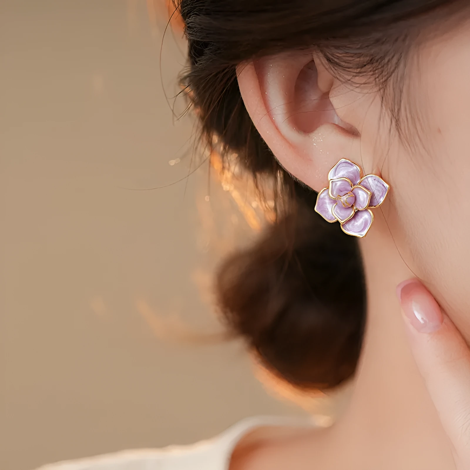 A pair of gold-plated purple oil-spot glaze flower stud earrings made from copper, showing detailed floral texture.