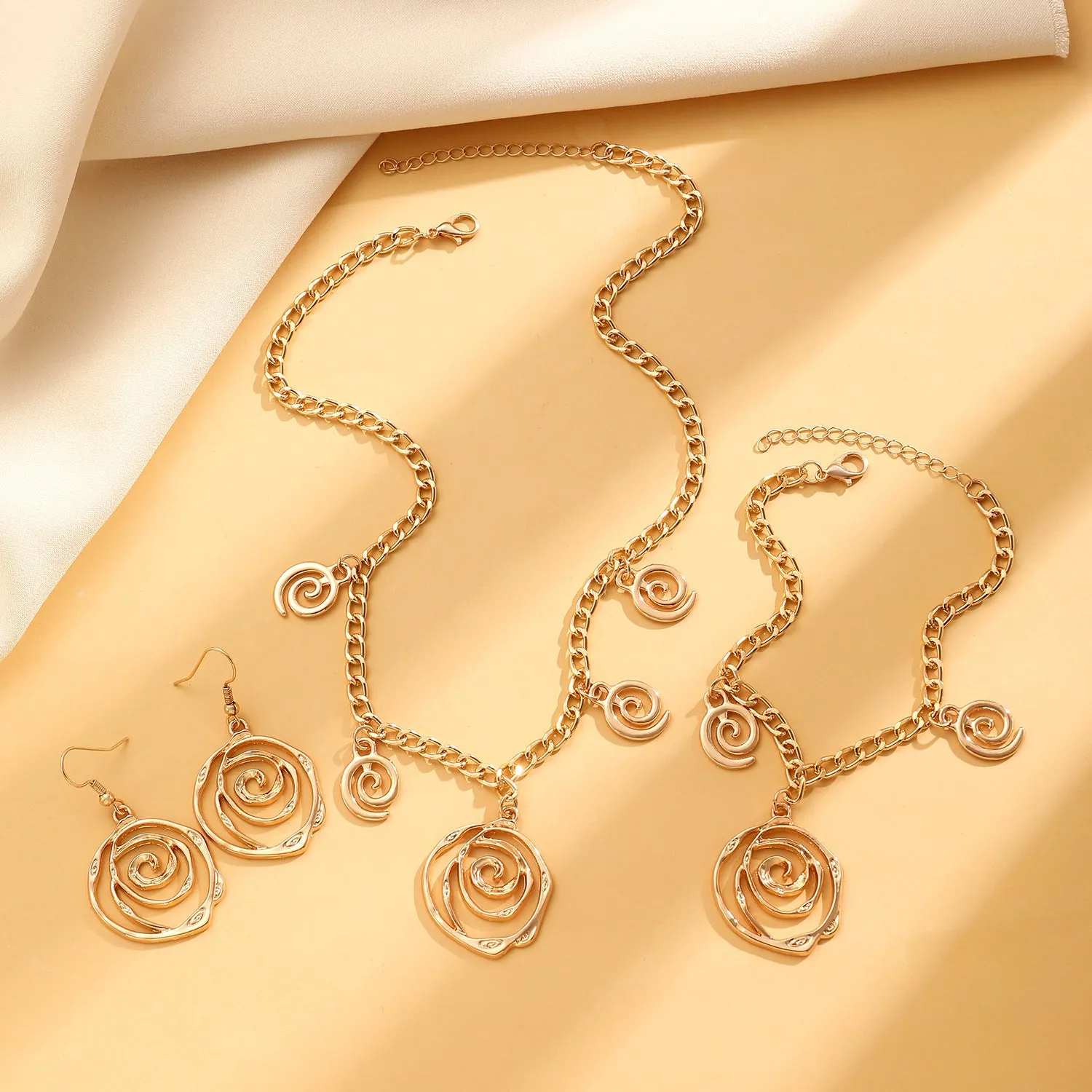 Spiral donut jewellery set showing necklace, bracelet, and ear hooks in gold or silver tone alloy