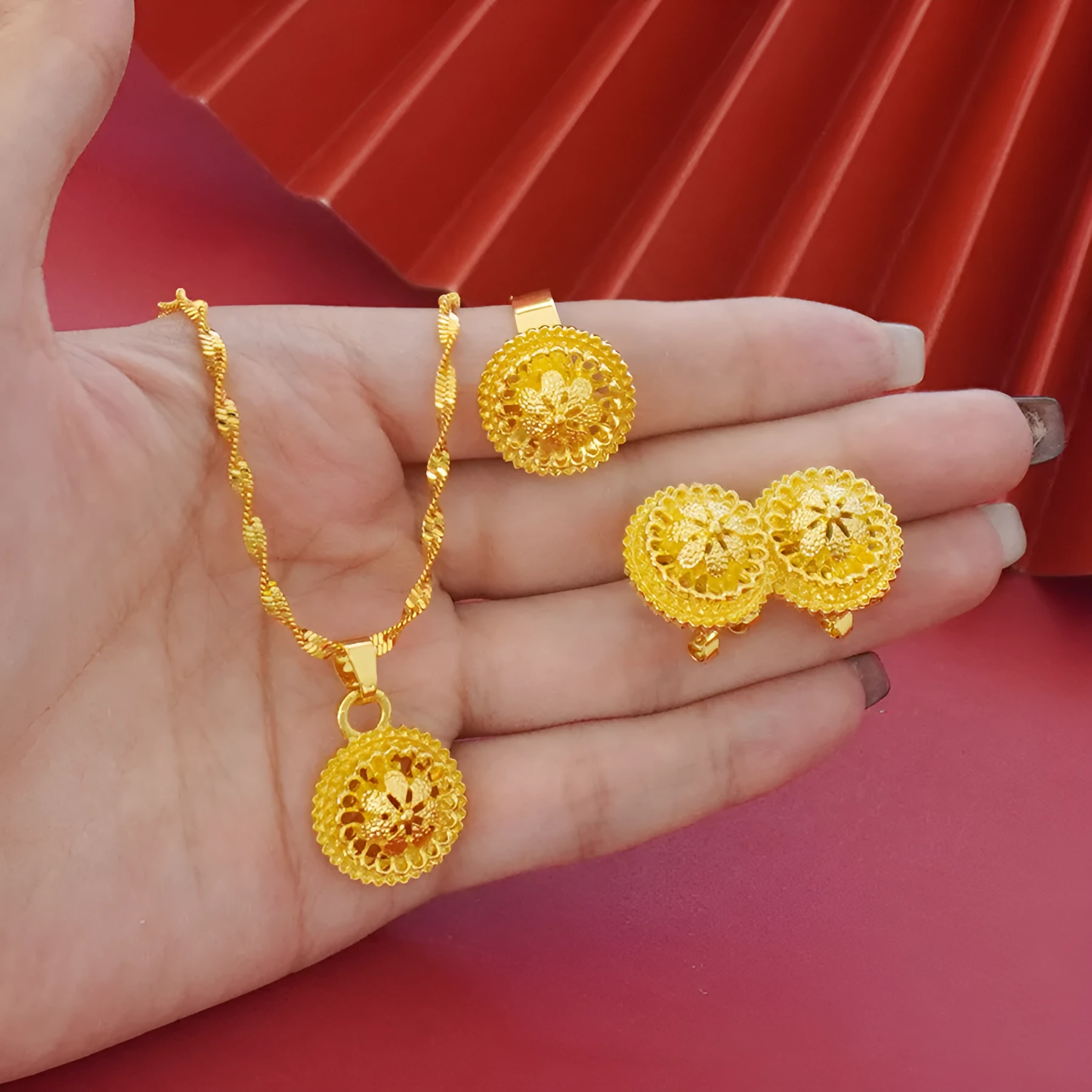 Gold-plated three-piece jewellery set with floral designs showing necklace, earrings, and ring