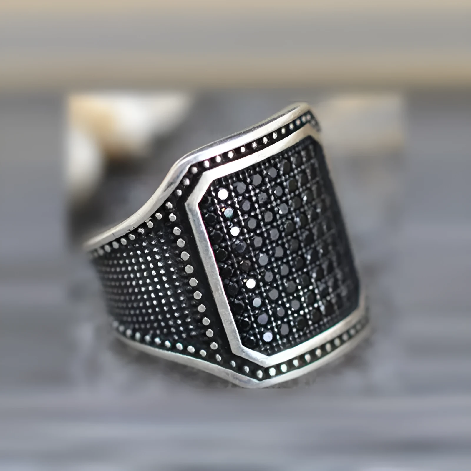 A black alloy ring with copper inlay and a centred zircon stone, shown on a finger.