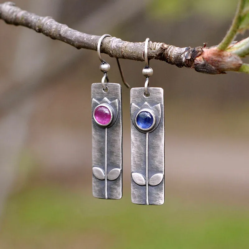 Antique finish metal stud earrings with a red sapphire in an ellipse shape, retro style.