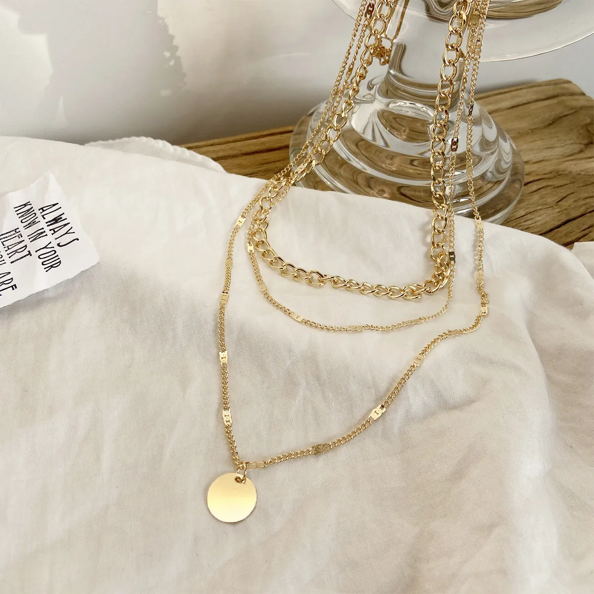 Women's multilayer disc pendant clavicle necklace in gold and silver colour finish on a light background