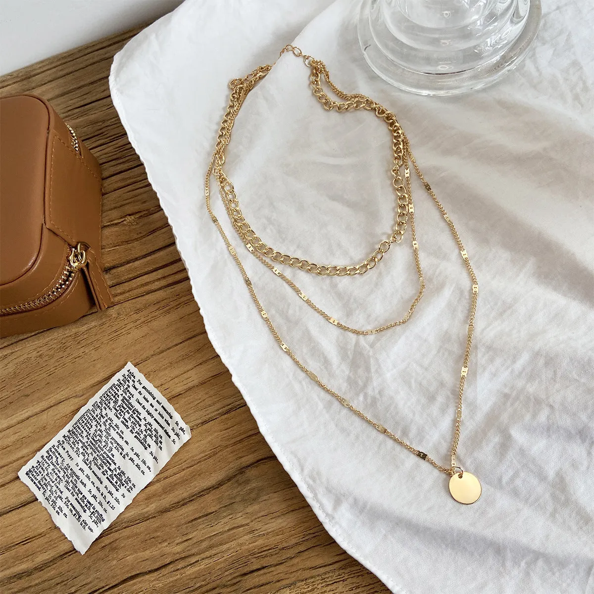 Women's multilayer disc pendant clavicle necklace in gold and silver colour finish on a light background