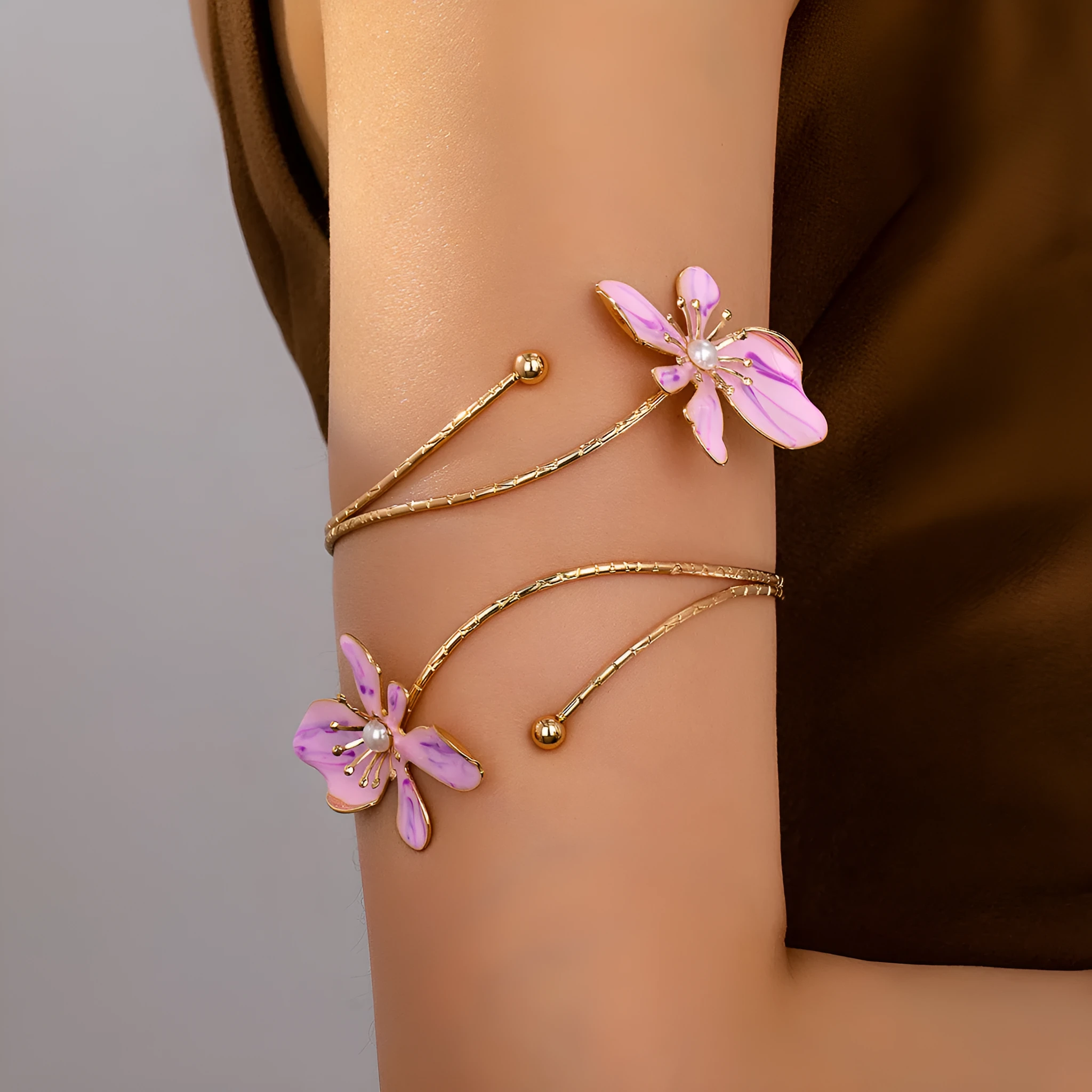 Close-up of a pink alloy armband with a hollow lines pattern, shown on a wrist.