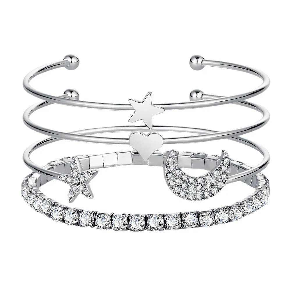 Four gold and silver metal cuff bracelets with moon and star designs on a plain background