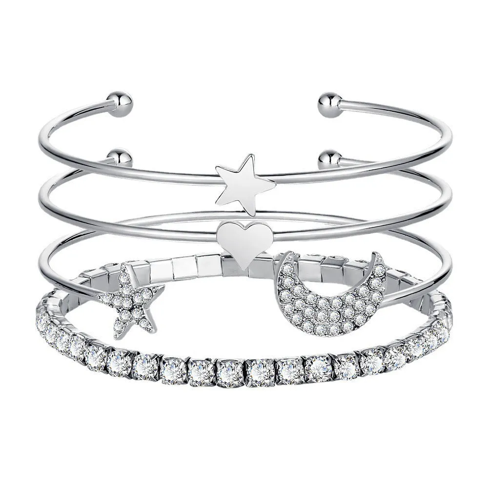 Four gold and silver metal cuff bracelets with moon and star designs on a plain background