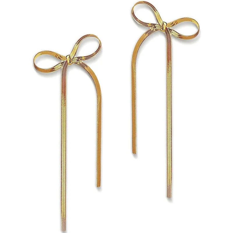 Gold plated bow ribbon dangle earrings with tassel tails on white background