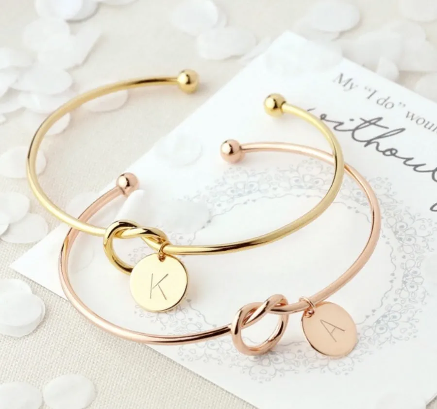 Personalised initial heart knot bracelet in gold finish with custom letter on a white background