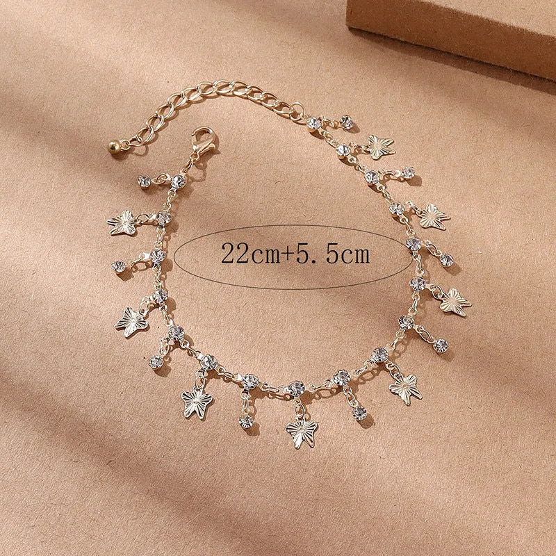 Gold alloy butterfly tassel anklet with colourful floral and leaf design on foot for summer beach wear