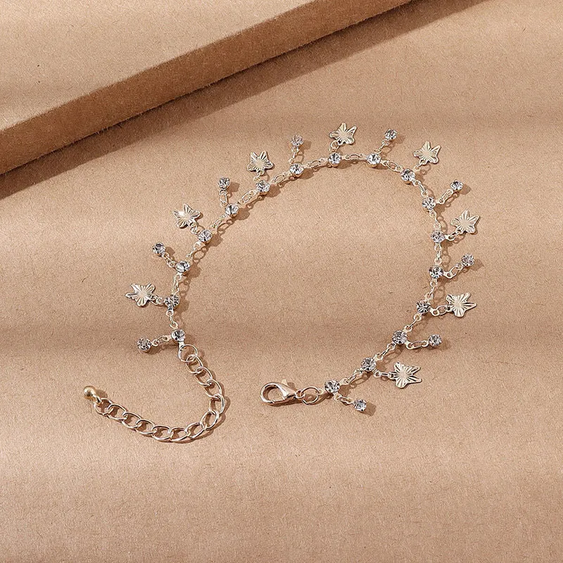 Gold alloy butterfly tassel anklet with colourful floral and leaf design on foot for summer beach wear