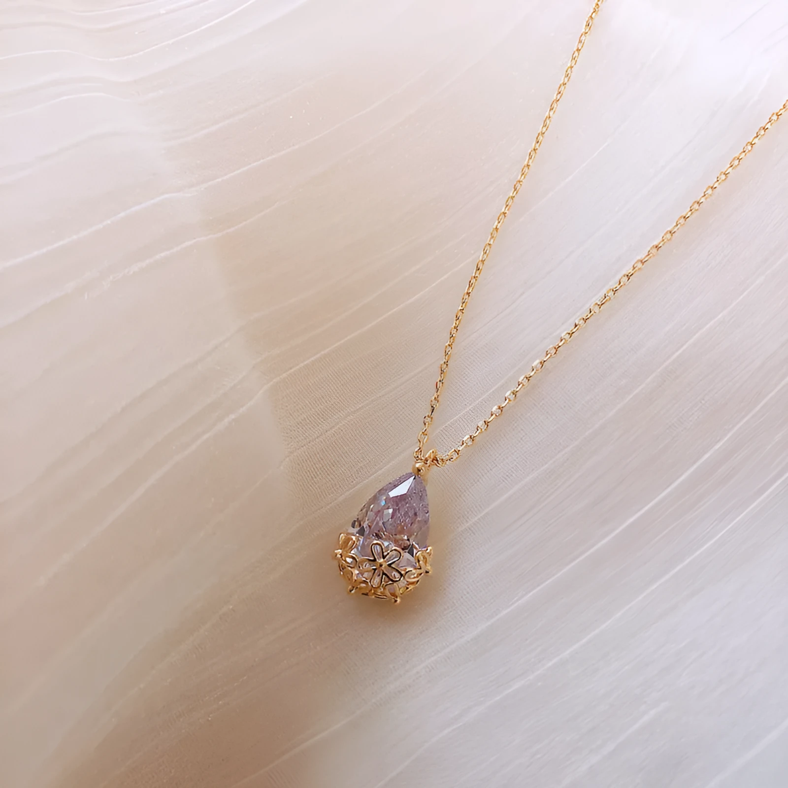Crystal water drop pendant necklace on a woman, adjustable silver plated chain, clear drop shape pendant close up