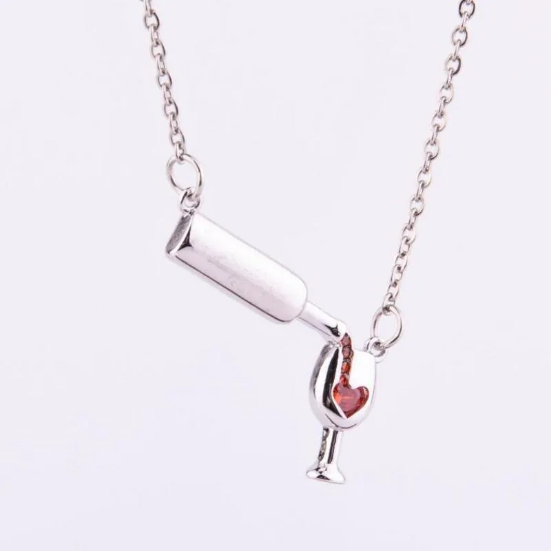 Gold alloy wine bottle and glass pendant necklace on a light background