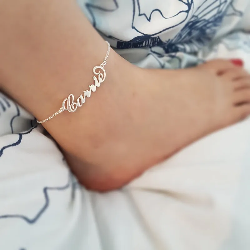 Gold titanium steel cable chain anklet with personalised name engraving on a sandy beach background