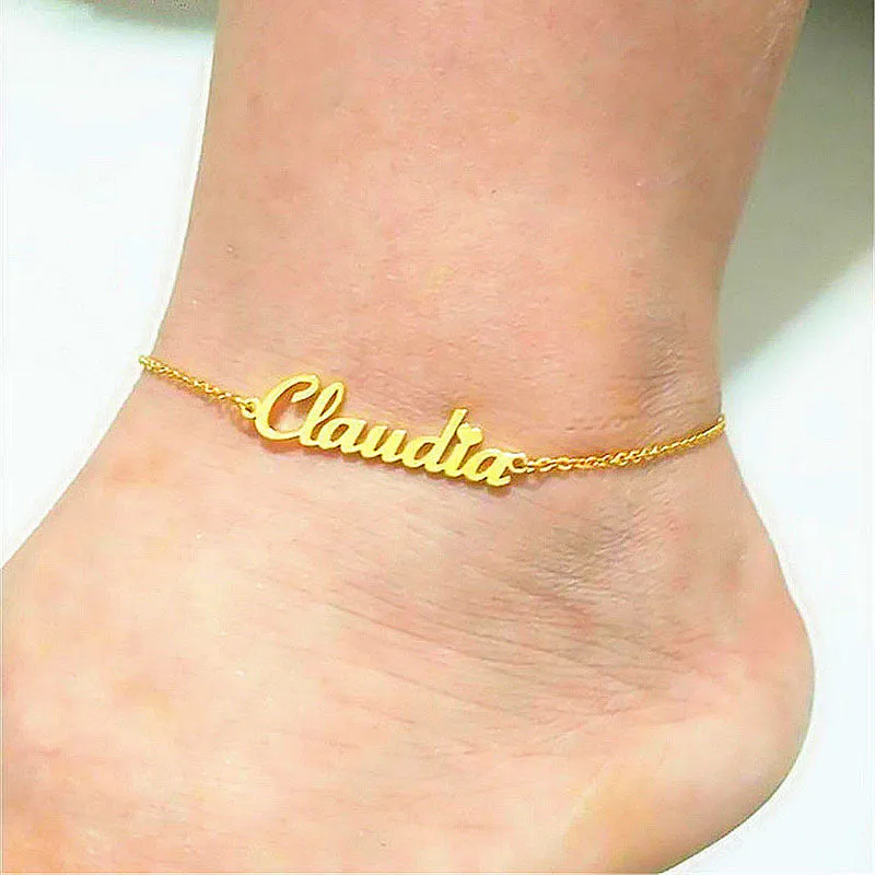 Gold titanium steel cable chain anklet with personalised name engraving on a sandy beach background