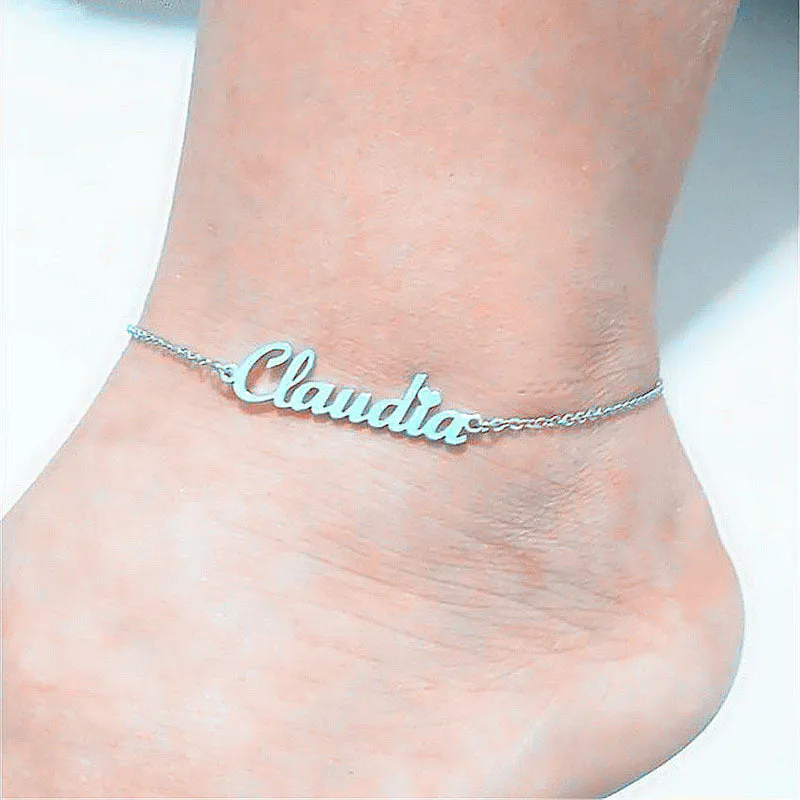 Gold titanium steel cable chain anklet with personalised name engraving on a sandy beach background