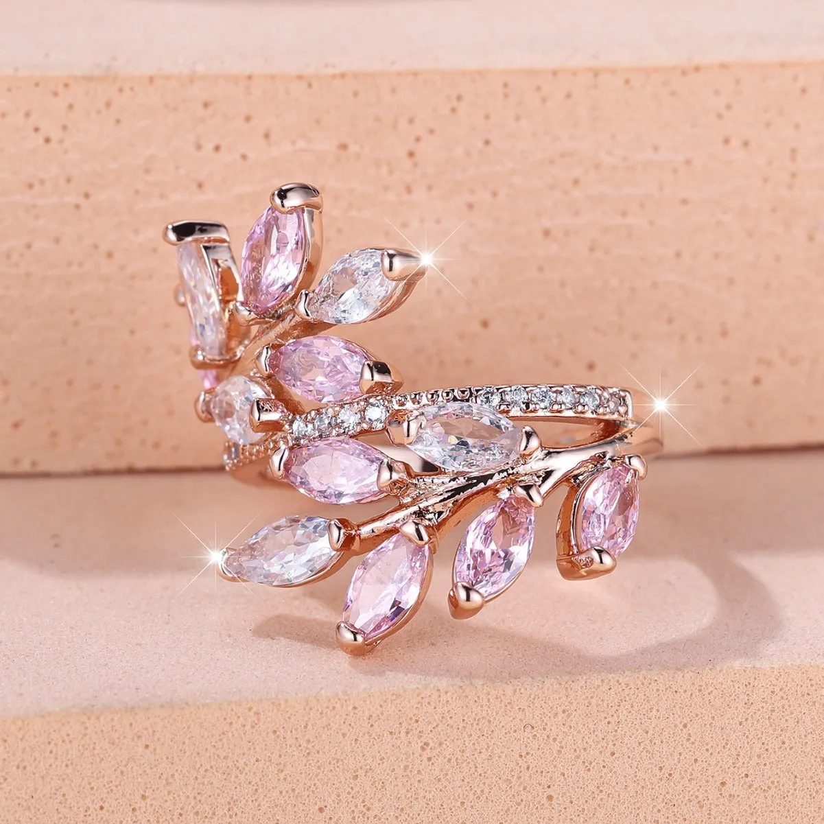 Adjustable copper leaf fashion ring with a central zircon stone on a model's hand, showing rose gold and platinum colour variants.